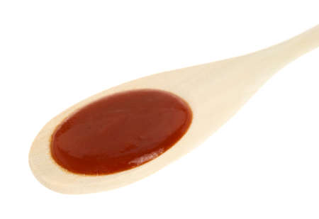 A wood spoon filled with red taco sauce on a white background.の写真素材