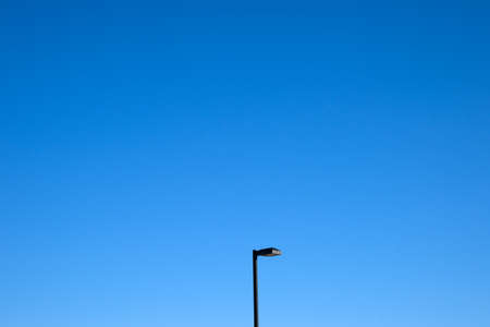 A lone street light against a bright blue sky.