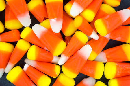 A very close view of Halloween candy corn kernels on a dark background.の写真素材
