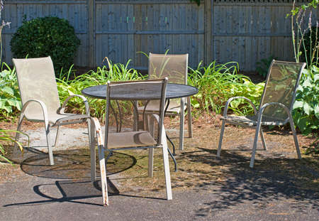 A setting of outdoor lawn furniture on asphalt with four chairs and a wire mesh table in a garden setting.の写真素材