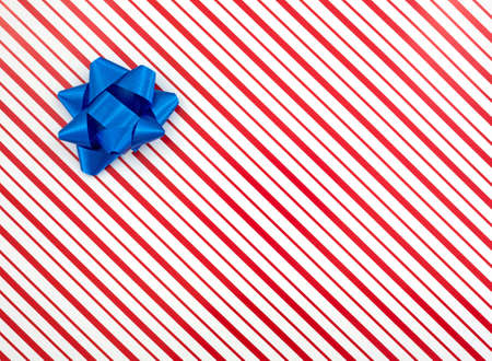Top view of a Christmas red and white striped box with a blue bow.