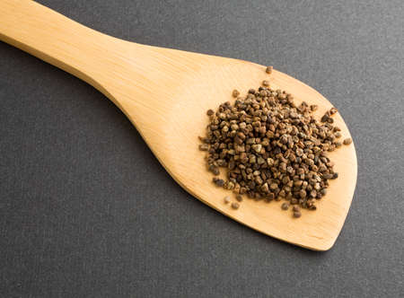 A wood spoon with a portion of cardamom seeds on a dark background.の写真素材