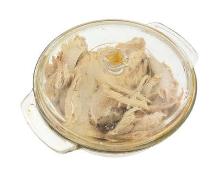 An old covered glass dish filled with leftover turkey on a white background.の写真素材