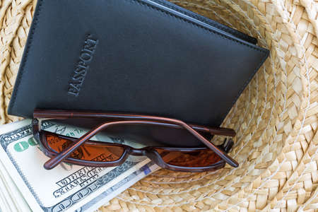 A straw hat with a leather passport holder, sunglasses and vacation cash.の写真素材
