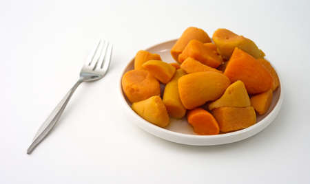 A plate of canned yams on a white table top with a fork to the side.の写真素材