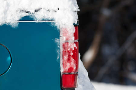 Snow covering parts of an old truck with a red taillight.の写真素材