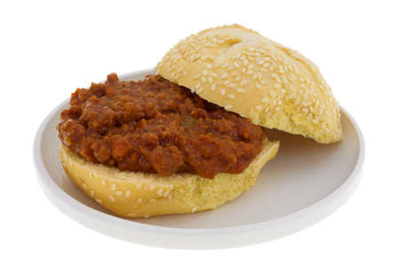 A sesame seed roll with sloppy joe mix open on a small plate isolated on a white background.の写真素材