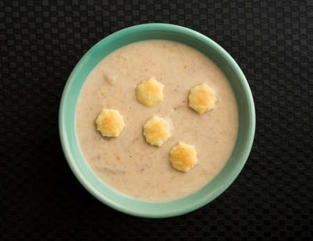 Top view of a bowl filled with lobster corn chowder atop black table cloth.の写真素材