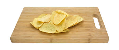A small serving of sour cream and chive flavored potato chips on a wood cutting board isolated on a white background.の写真素材