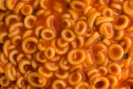 A very close view of canned round spaghetti pasta in tomato sauce illuminated by natural light.の写真素材