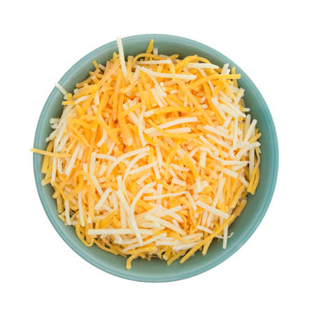 Top view of a small bowl filled with shredded white cheddar, sharp cheddar and mild cheddar cheeses isolated on a white background.の写真素材