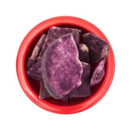 Top view of a red bowl filled with freeze dried apple slices coated with Maqui berry powder isolated on a white background.の写真素材