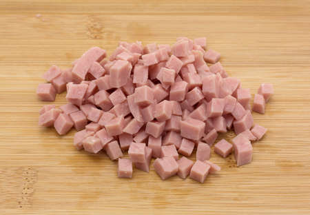 A portion of diced ham on a wood cutting board.の写真素材