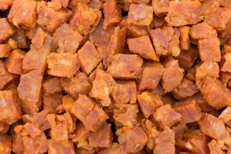 A very close view of pepperoni pizza topping that has been chopped into small cubes.