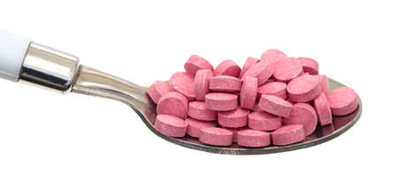 A large spoonful of vitamin B12 tablets on a white background.の写真素材
