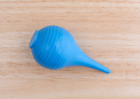 Top view of a new blue plastic ear syringe for ear wax removal on a wood table top.の写真素材