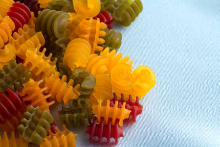 Close view of a portion of gluten free corn vegetable radiatore pasta spilled onto a blue cloth...