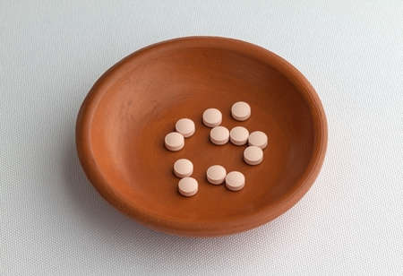 A group of famotidine tablets in a small bowl on an off white table cloth.の写真素材