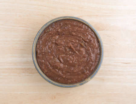 Top view of a bowl filled with black bean dip atop a wood table top.の写真素材