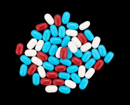 An assortment of red white and blue breath mints on a black background.