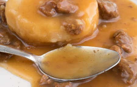 Close view of a mashed potatoes in gravy with beef tips TV dinner with a spoon on a plate.の写真素材