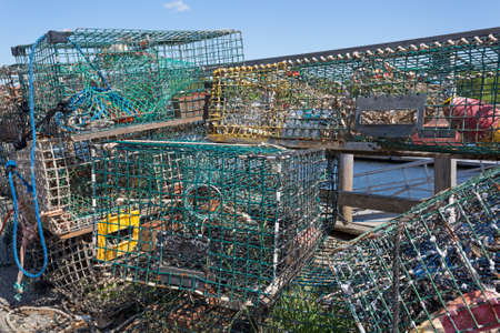 Several lobster traps stacked in an jumble on a working dock in the late spring at Belfast, Maine.の写真素材