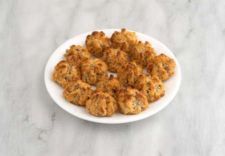 Several chocolate chip macaroons on a white plate atop a marble table top.の写真素材