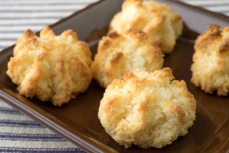 A very close view of sugar free coconut macaroons in a small dish atop a blue striped tablecloth.の写真素材