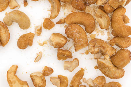 Top close view of pieces of honey roasted cashews on a white plate with crumbs and salt.の写真素材