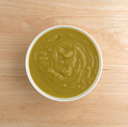 Top view of a bowl of thick green pea soup on a wood table top.の写真素材