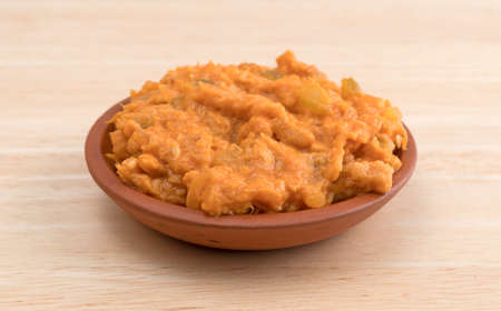 A portion of spicy chicken salad in a small bowl on a wood table top.の写真素材