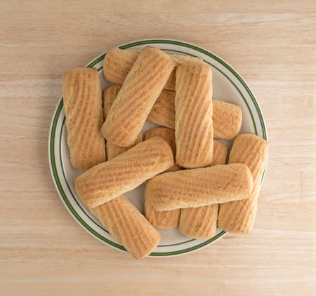 Top view of a group of vanilla cookie bars on a green striped plate atop a wood table.の写真素材