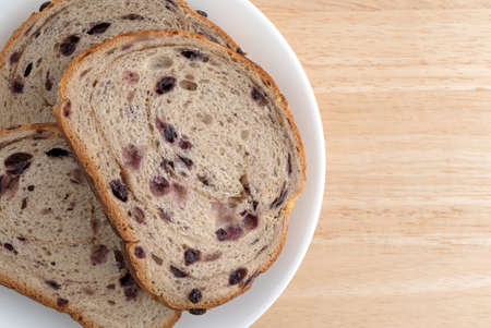 Top close view of several slices of blueberry streusel bread on a white plate atop a wood table top.の写真素材