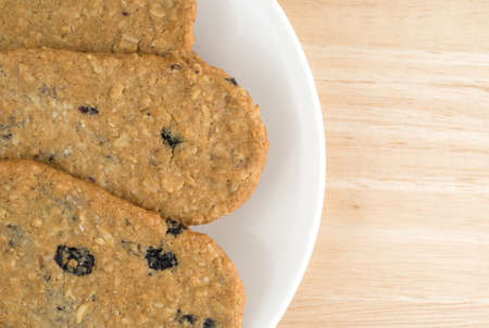 Top close view of blueberry wafer cookies on a white plate atop a wood table top.の写真素材