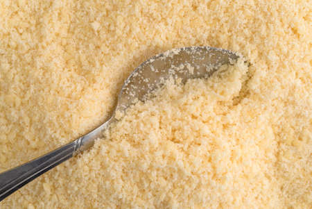 Close view of a spoon in freshly grated parmesan cheese.の写真素材