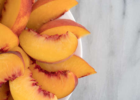 Top view of nectarine slices on a white plate atop a marble table.の写真素材