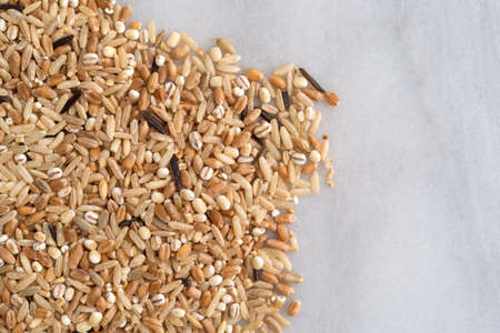 Top view of several varieties of rice and grains on a marble cutting board.の写真素材