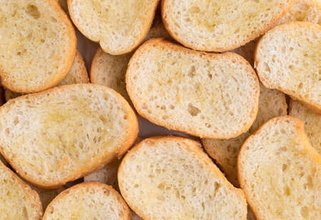 A very close view of crostini that has been dabbed with olive oil.