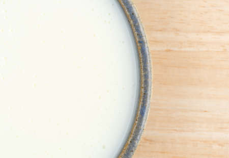 Top close view of a bowl of buttermilk on a wood table.