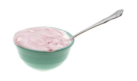 An overflowing bowl of raspberry yogurt with a spoon inserted into the food on a white background.の写真素材