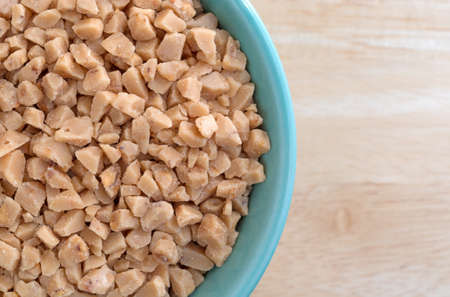 Top close view of a green bowl filled with toffee bits atop a wood table.の写真素材