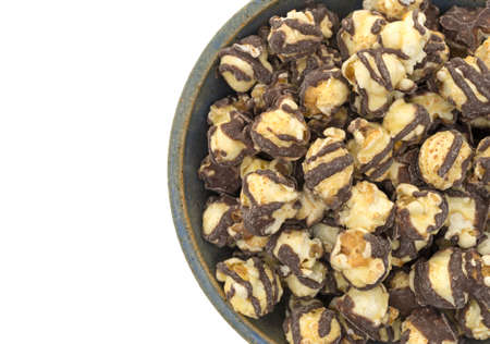 Top close view of a serving of fudge drizzled popcorn in an old stoneware bowl on a white background.の写真素材