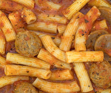 A very close view of rigatoni pasta with sausage and meatballs in a marinara sauce.の写真素材