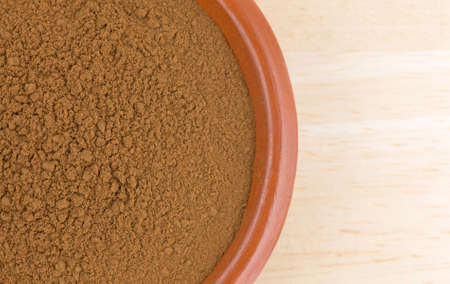 Top close view of a small serving of carob powder in a bowl on a wood table top.の写真素材