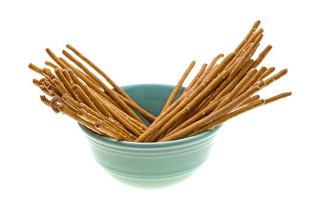 Salted whole wheat bretzel sticks in a green bowl isolated on a white background.の写真素材