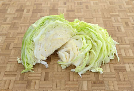A portion of organic cabbage that has been sliced on a wood cutting board.の写真素材