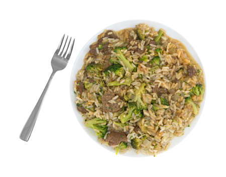 Top view of beef with broccoli and rice in a sauce on a plate with a fork to the side isolated on a white background.の写真素材