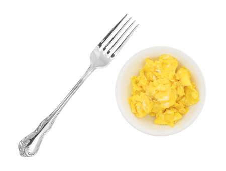 A small bowl filled with freshly made scrambled eggs and a fork to the side isolated on a white background.の写真素材