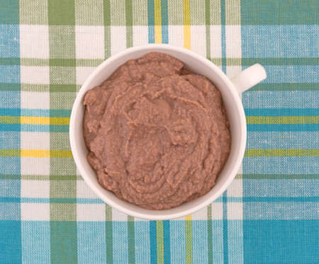 Top view of a white cup filled with a berry blended yogurt smoothie atop a colorful patterned place mat.の写真素材