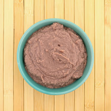 Top view of a green bowl filled with a berry blended yogurt smoothie on a wood place mat.